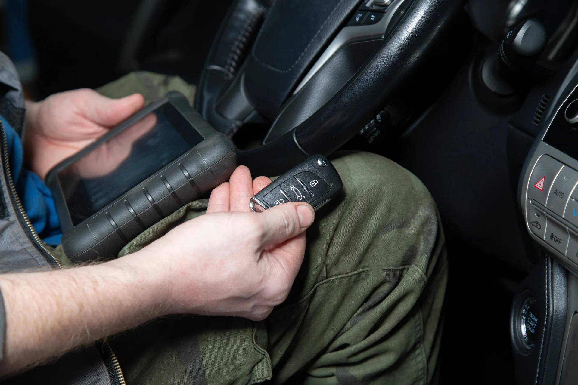 Person holding car key and diagnostic tool.